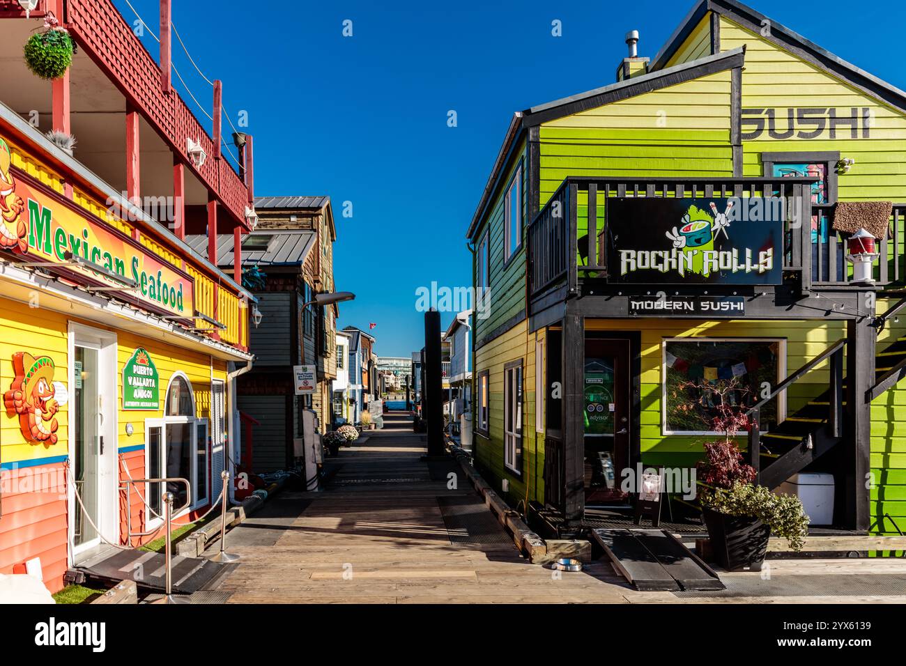 Una piccola città con un edificio verde che dice Rockin' bella. La strada è fiancheggiata da edifici colorati e da alcune piante in vaso Foto Stock