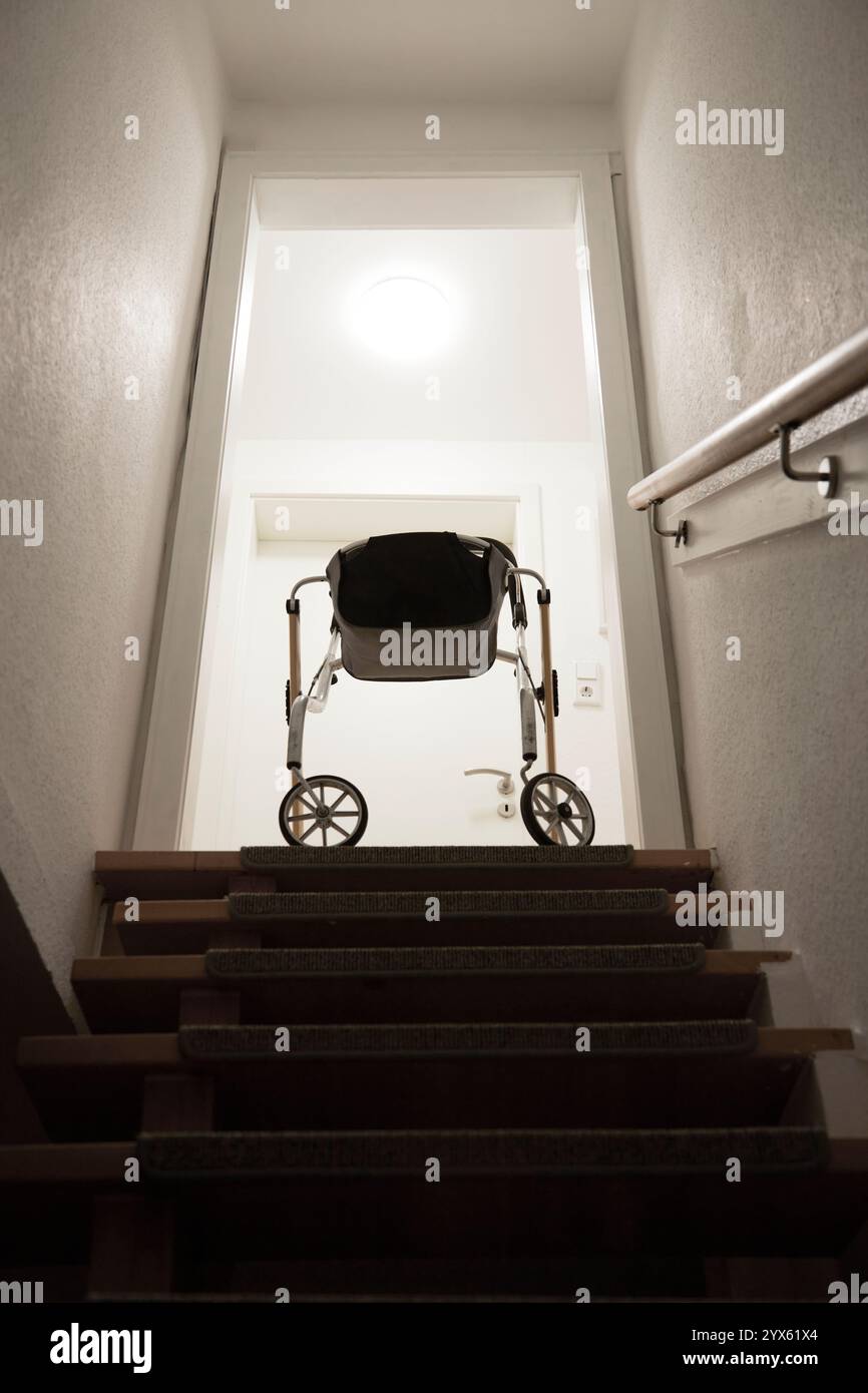 walker alla fine di una scala come simbolo di ostacoli che gli anziani non possono superare senza aiuto Foto Stock