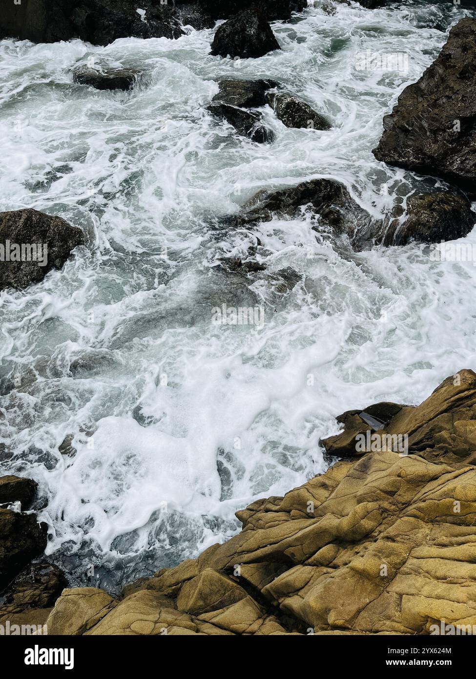 Le onde oceaniche dinamiche si schiantano contro la costa rocciosa - Immagine stock catturata con smartphone