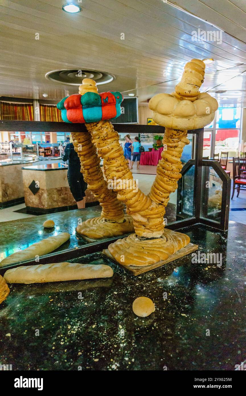 Una grande scultura di pane è in mostra in un ristorante. Il pane ha la forma di un albero e ha una persona sopra di esso. La scultura e' circondata da Foto Stock Una grande scultura di pane è in mostra in un ristorante. Il pane ha la forma di un albero e ha una persona sopra di esso. La scultura e' circondata da Foto Stock