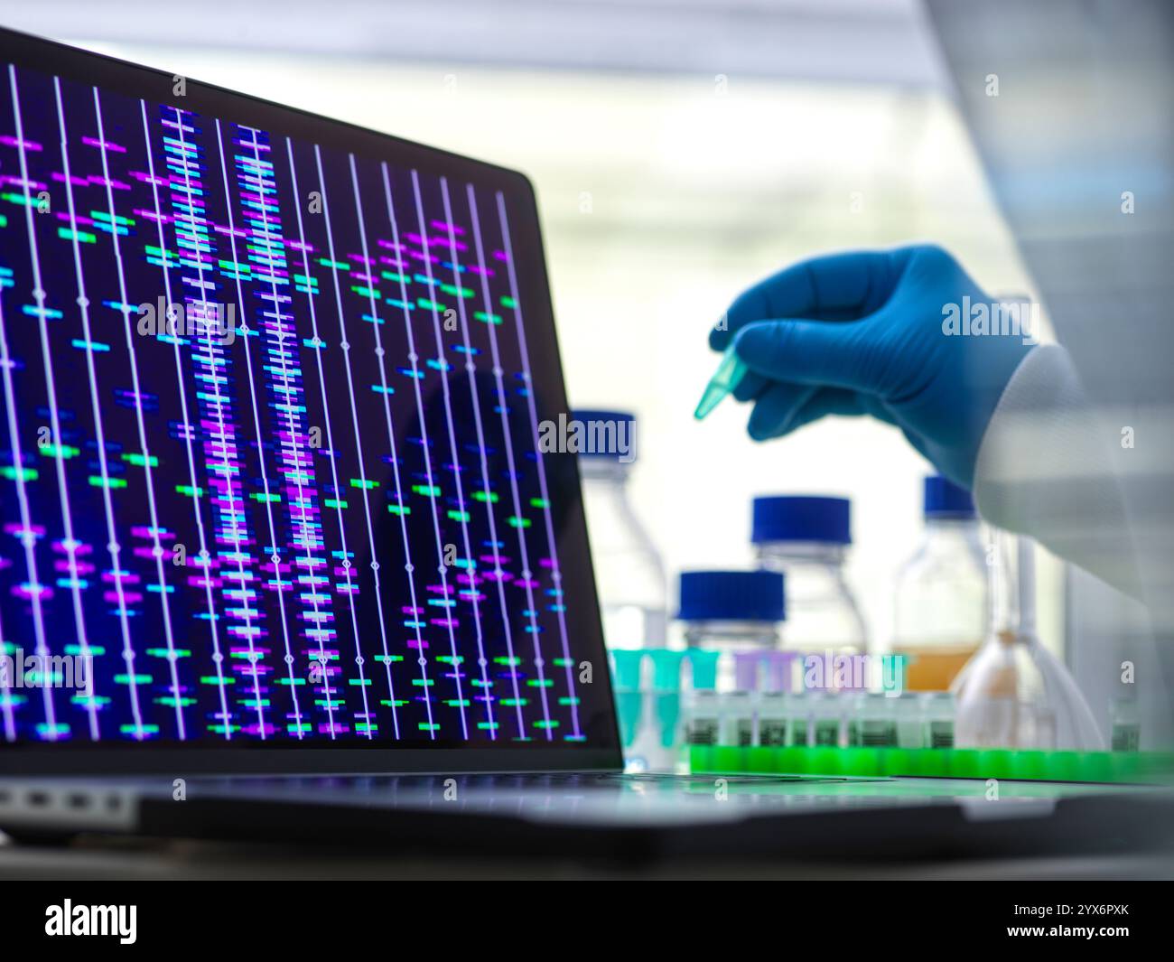 Scienziato che prepara un campione di DNA (acido deossiribonucleico) per l'analisi, con un profilo DNA sullo schermo. Foto Stock
