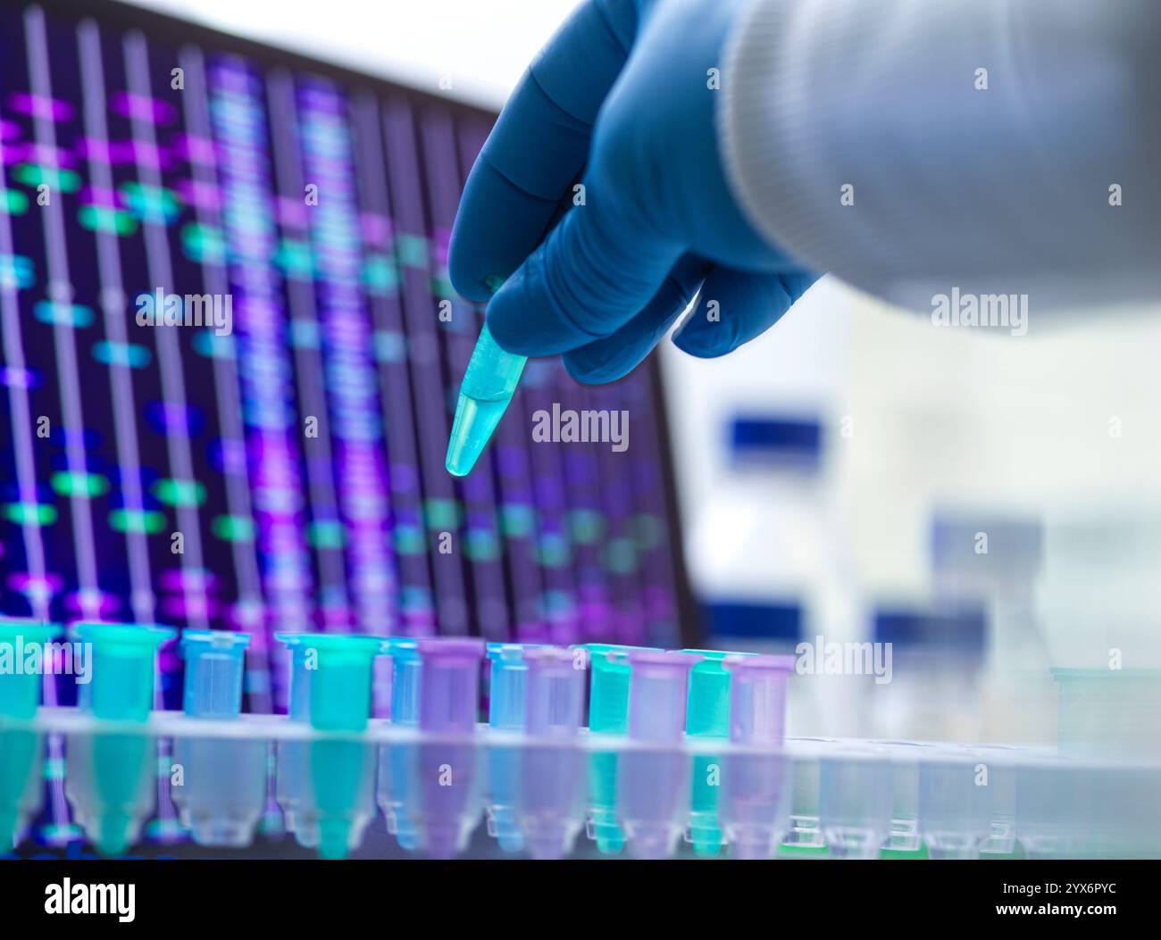 Scienziato che prepara un campione di DNA (acido deossiribonucleico) per l'analisi, con un profilo DNA sullo schermo. Foto Stock