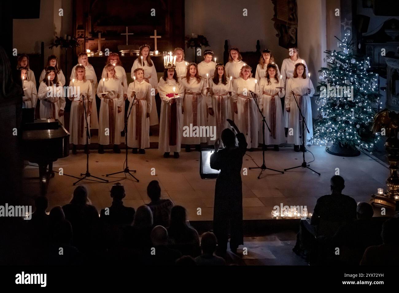 Londra, Regno Unito. 13 dicembre 2024. Sankta Lucia celebrazioni del Coro svedese Norrsång East London presso la chiesa di St Mary a Walthamstow. Alma Fridell Crawshaw indossa una corona di candele che simboleggiano Santa Lucia mentre conduce la celebrazione di Sankta Lucia, basata sul coraggio e il martirio di una giovane ragazza siciliana Santa Lucia (Lucia di Siracusa 283-304). Crediti: Guy Corbishley/Alamy Live News Foto Stock