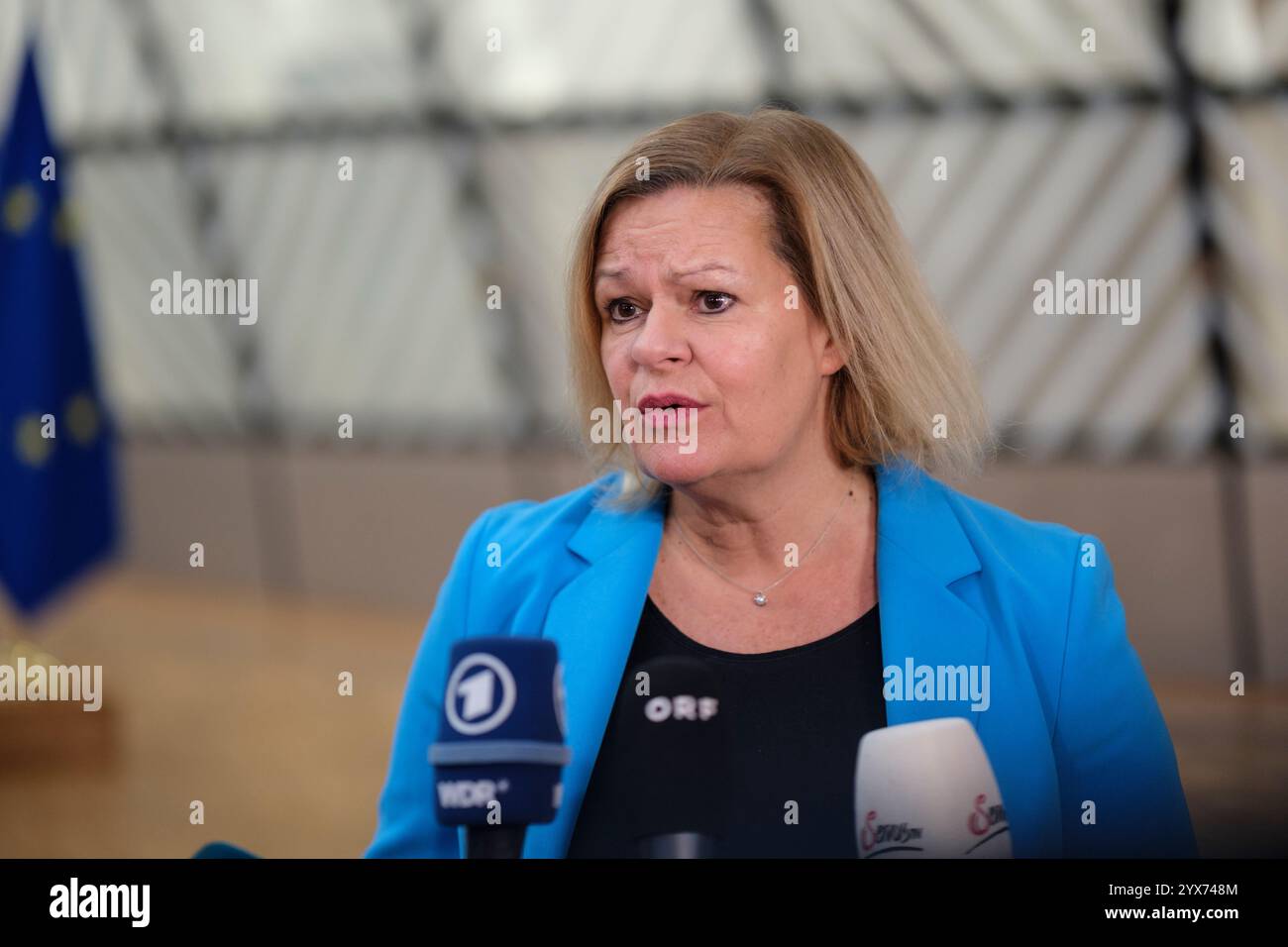 12 dicembre 2024, Belgio, Brüssel: Il ministro federale tedesco degli interni e della Comunità Nancy Faeser sta parlando con i media prima dell'inizio di una riunione dei ministri degli interni dell'Unione europea presso la sede del Consiglio dell'Unione europea. La Presidenza ha iscritto all'ordine del giorno della riunione dei ministri l'adozione della decisione del Consiglio che fissa la data per la revoca dei controlli sulle persone alle frontiere terrestri interne con e tra Bulgaria e Romania. Foto: Thierry Monasse/dpa Foto Stock
