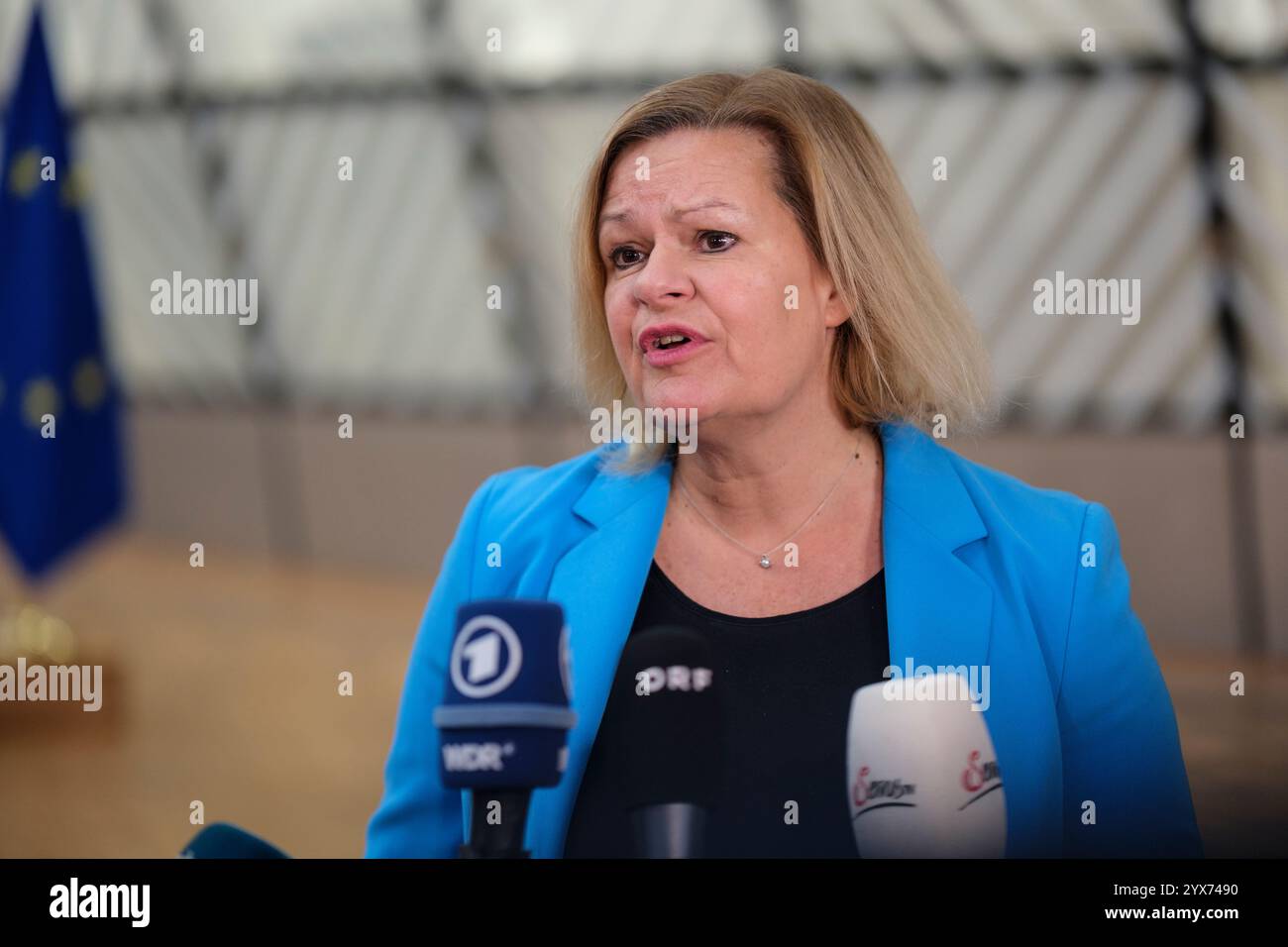 12 dicembre 2024, Belgio, Brüssel: Il ministro federale tedesco degli interni e della Comunità Nancy Faeser sta parlando con i media prima dell'inizio di una riunione dei ministri degli interni dell'Unione europea presso la sede del Consiglio dell'Unione europea. La Presidenza ha iscritto all'ordine del giorno della riunione dei ministri l'adozione della decisione del Consiglio che fissa la data per la revoca dei controlli sulle persone alle frontiere terrestri interne con e tra Bulgaria e Romania. Foto: Thierry Monasse/dpa Foto Stock