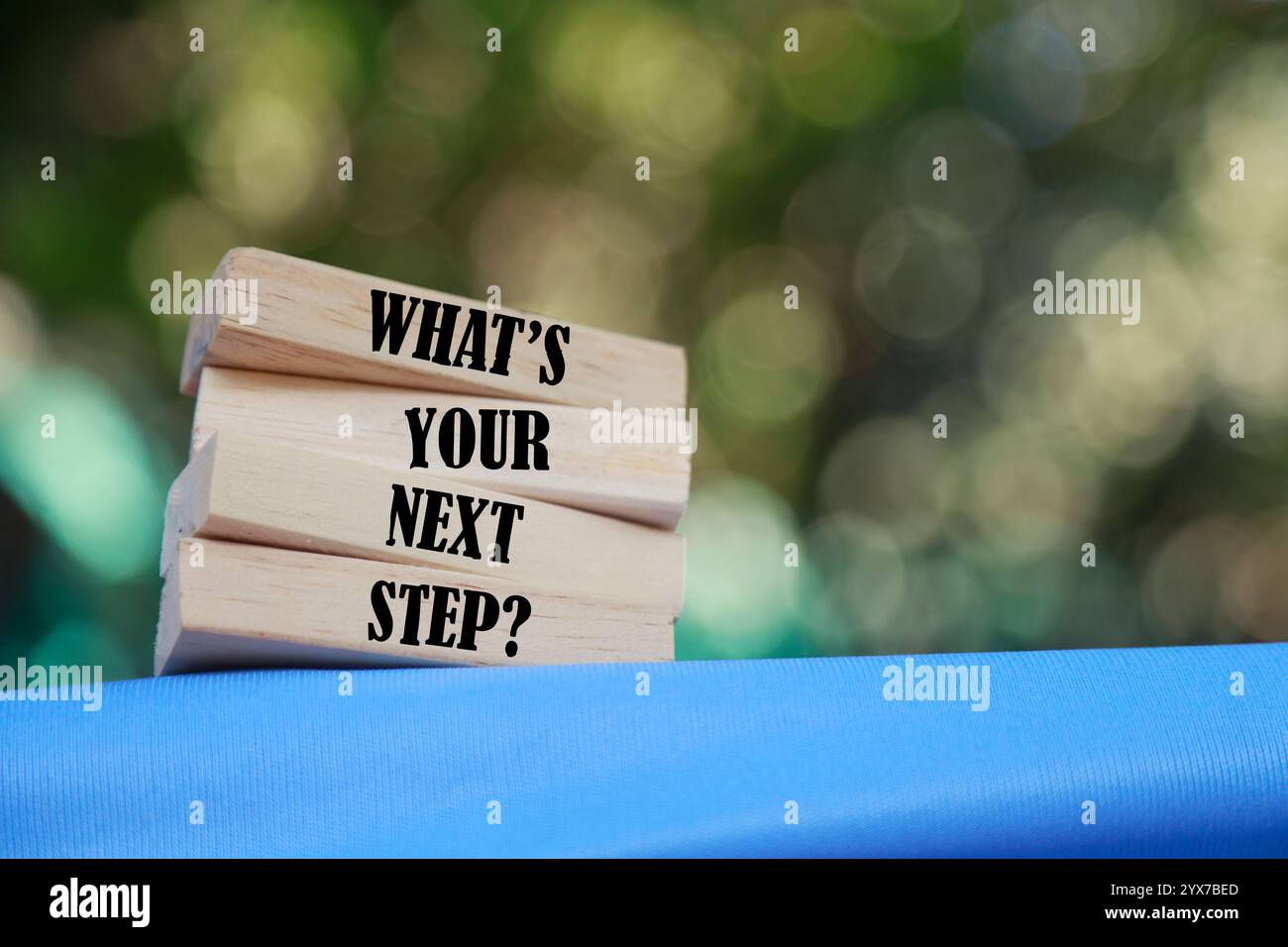 Qual è il simbolo del passo successivo? Blocchi di legno con parole qual è il tuo prossimo passo. Splendido sfondo blu e sfocato. Concetto di business. Copia spazio. Foto Stock