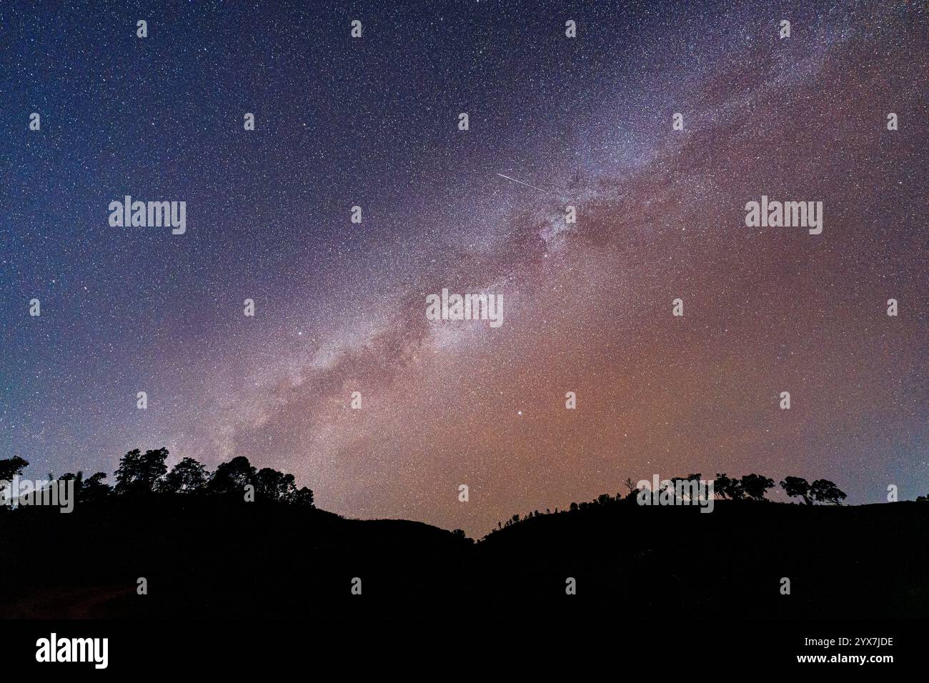 La via Lattea colorata con stelle che brillano nella galassia cosmica sopra le montagne nella remota natura selvaggia Foto Stock