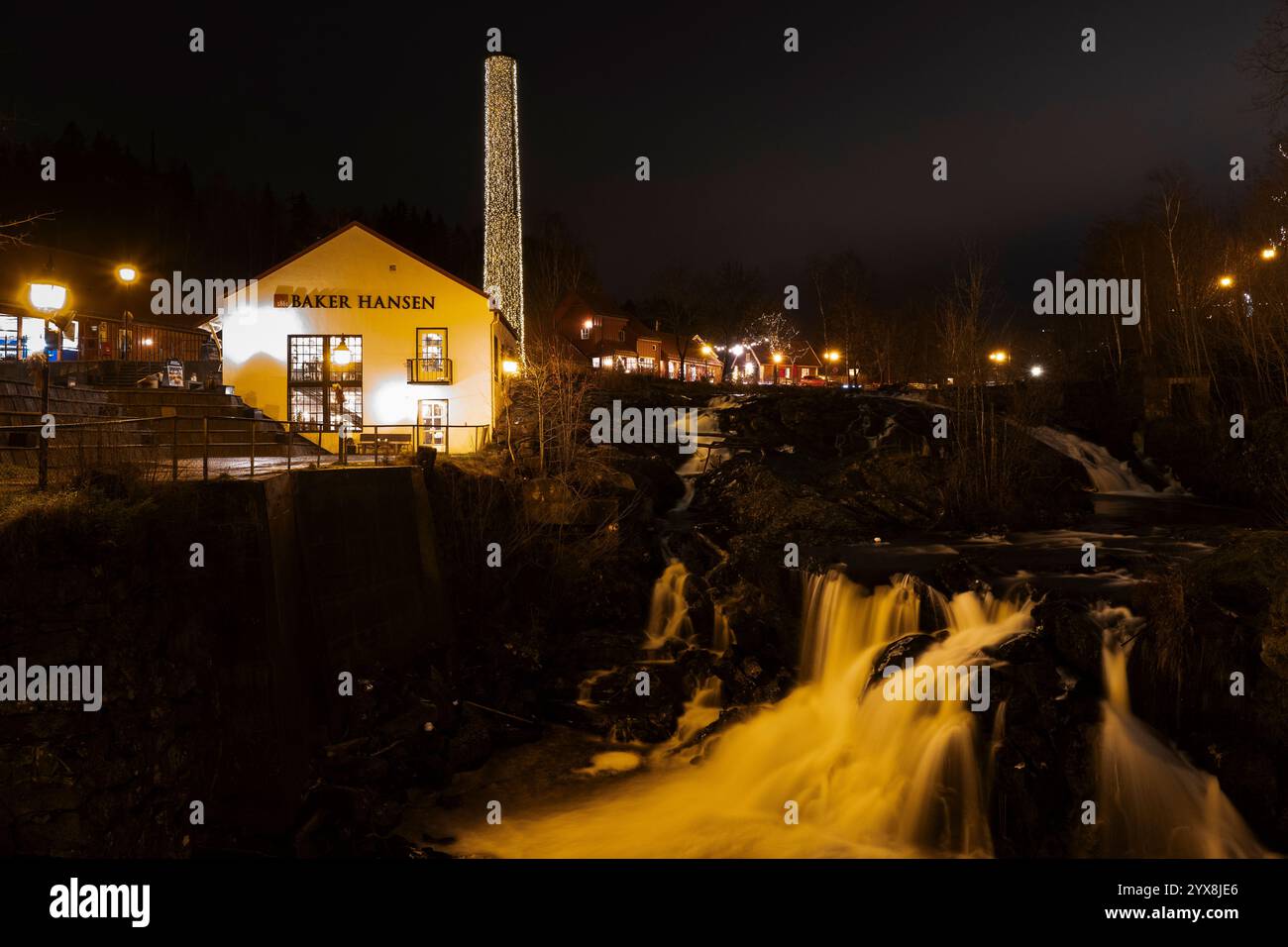 Scena della notte di Natale di una cascata vicino alla panetteria Baker Hansen a Bærums Verk. La panetteria e il fiume sono splendidamente illuminati. Foto Stock