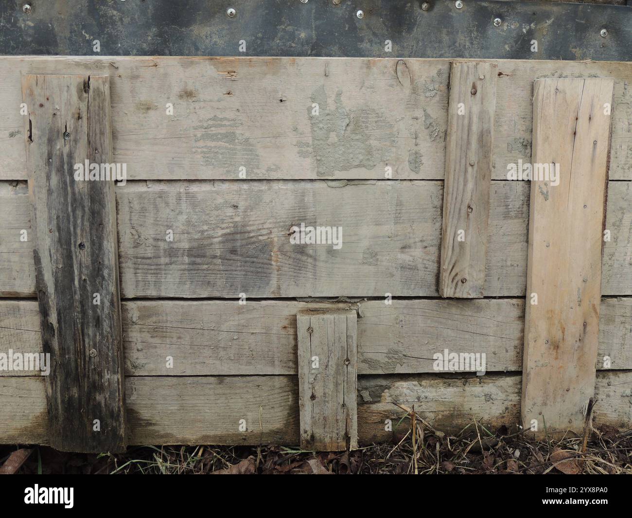 una vecchia recinzione bassa fatta di tavole di diverse dimensioni che si abbattono casualmente come una struttura in legno ruvido unica invecchiata dagli effetti del tempo Foto Stock