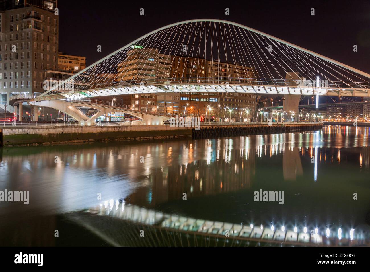 Notte al ponte Zubizuri progettato da Santiago Calatrava sul fiume Nervion a Bilbao, in Spagna, con le torri gemelle Isozaki Atea Foto Stock