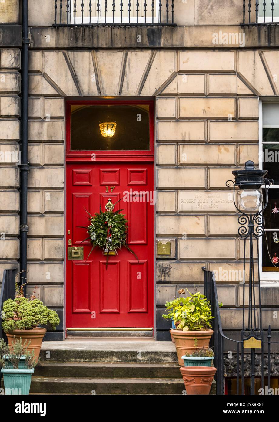 Porta rossa dipinta con pannelli frontali georgiani con fanlight e corona di Natale, ex casa di Robert Louis Stevenson, Edimburgo New Town, Scozia, Regno Unito Foto Stock
