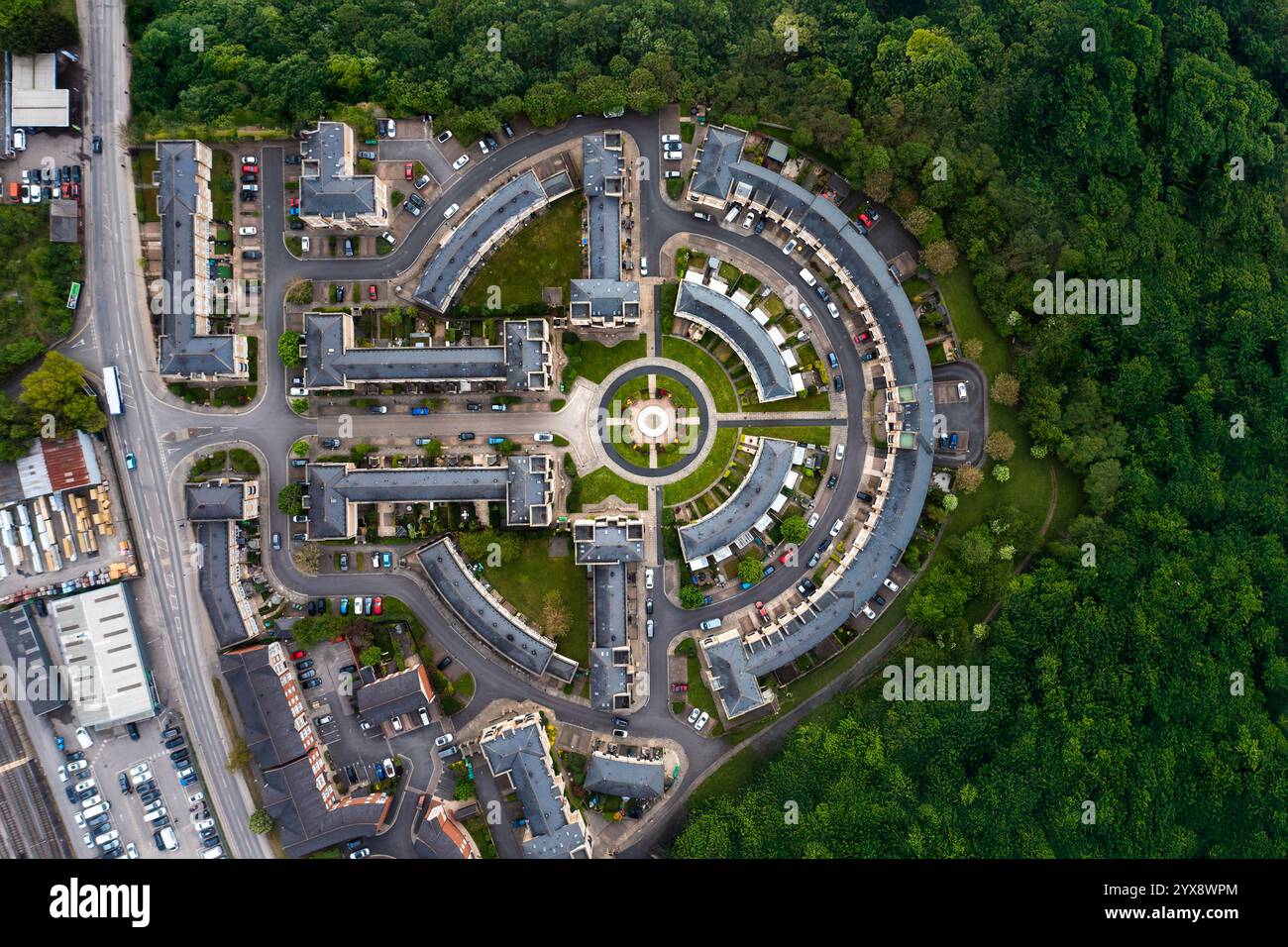 Vista aerea dall'alto verso il basso sopra un blocco di case suburbane di nuova costruzione nel Regno Unito con architettura curva centrata su un giardino circolare e destro Foto Stock