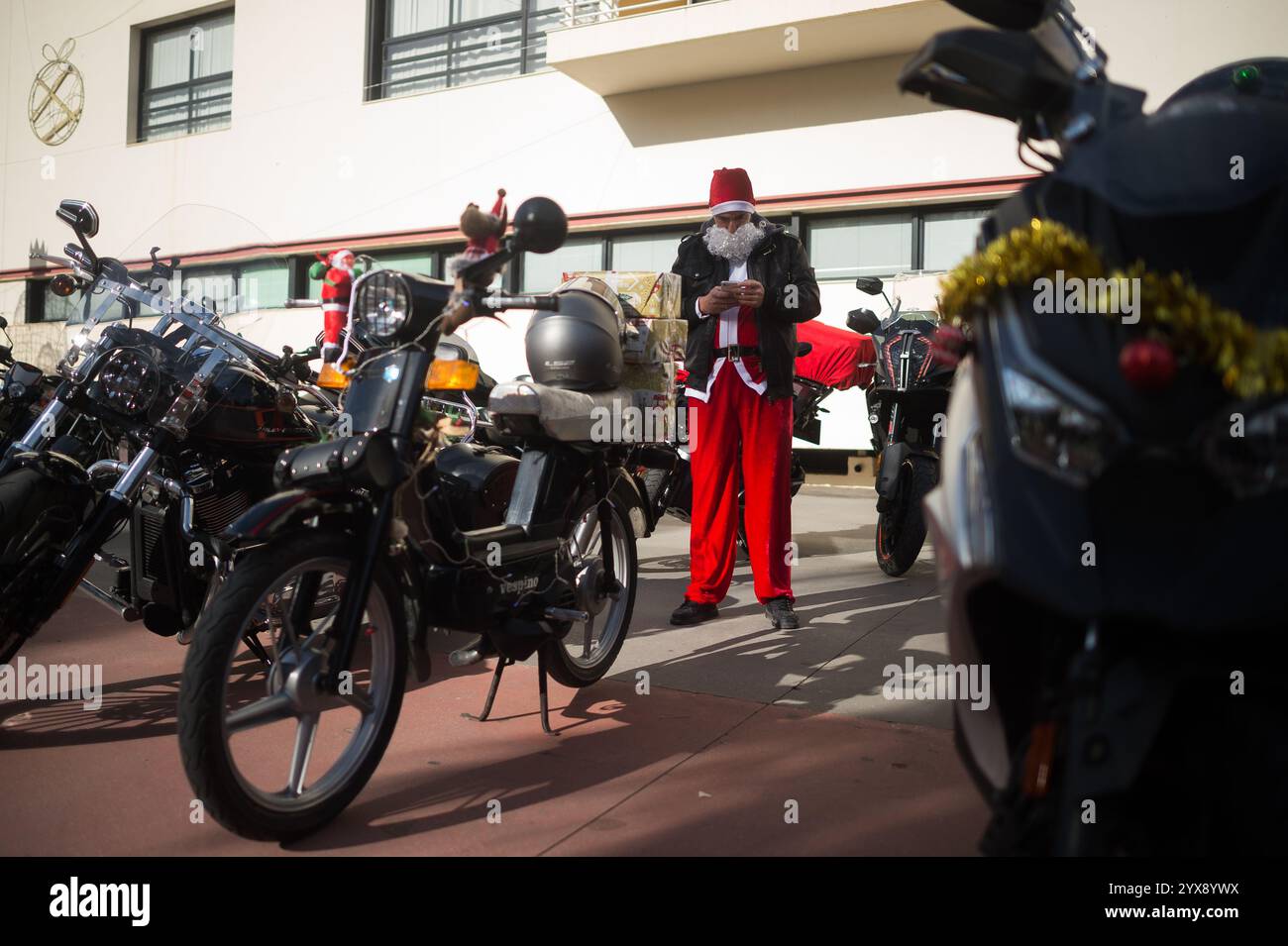 Malaga, Spagna. 14 dicembre 2024. Un uomo vestito da "Babbo Natale" viene visto controllare il suo cellulare prima di prendere parte all'X Toy Run Torremolinos. Centinaia di motociclisti e motociclisti si incontrano ogni anno nel centro di Torremolinos per partecipare a una gara di beneficenza vestita con costumi di Babbo Natale e collezionando giocattoli per bambini. (Foto di Jesus Merida/SOPA Images/Sipa USA) credito: SIPA USA/Alamy Live News Foto Stock
