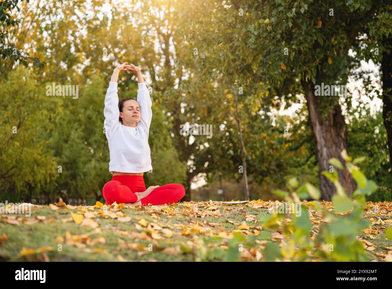 Donna che fa esercizio di yoga per alleviare lo stress in posa di loto all'aperto in natura. Foto Stock