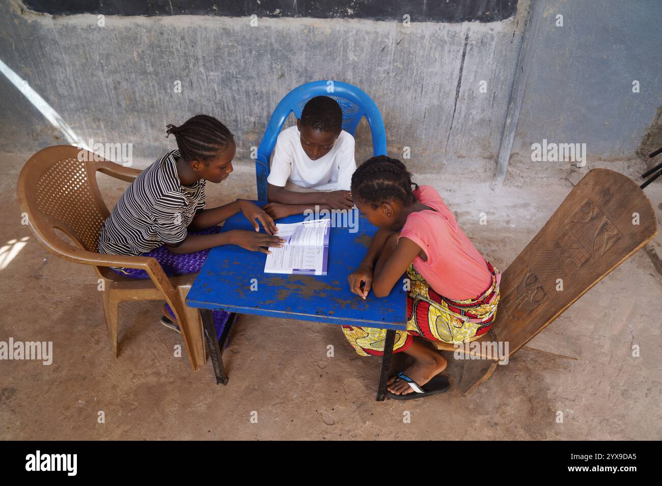 Gruppo di scolari dell'Africa occidentale imparano la lezione condividendo un unico libro - concetto di carenza di forniture scolastiche nei paesi in via di sviluppo Foto Stock