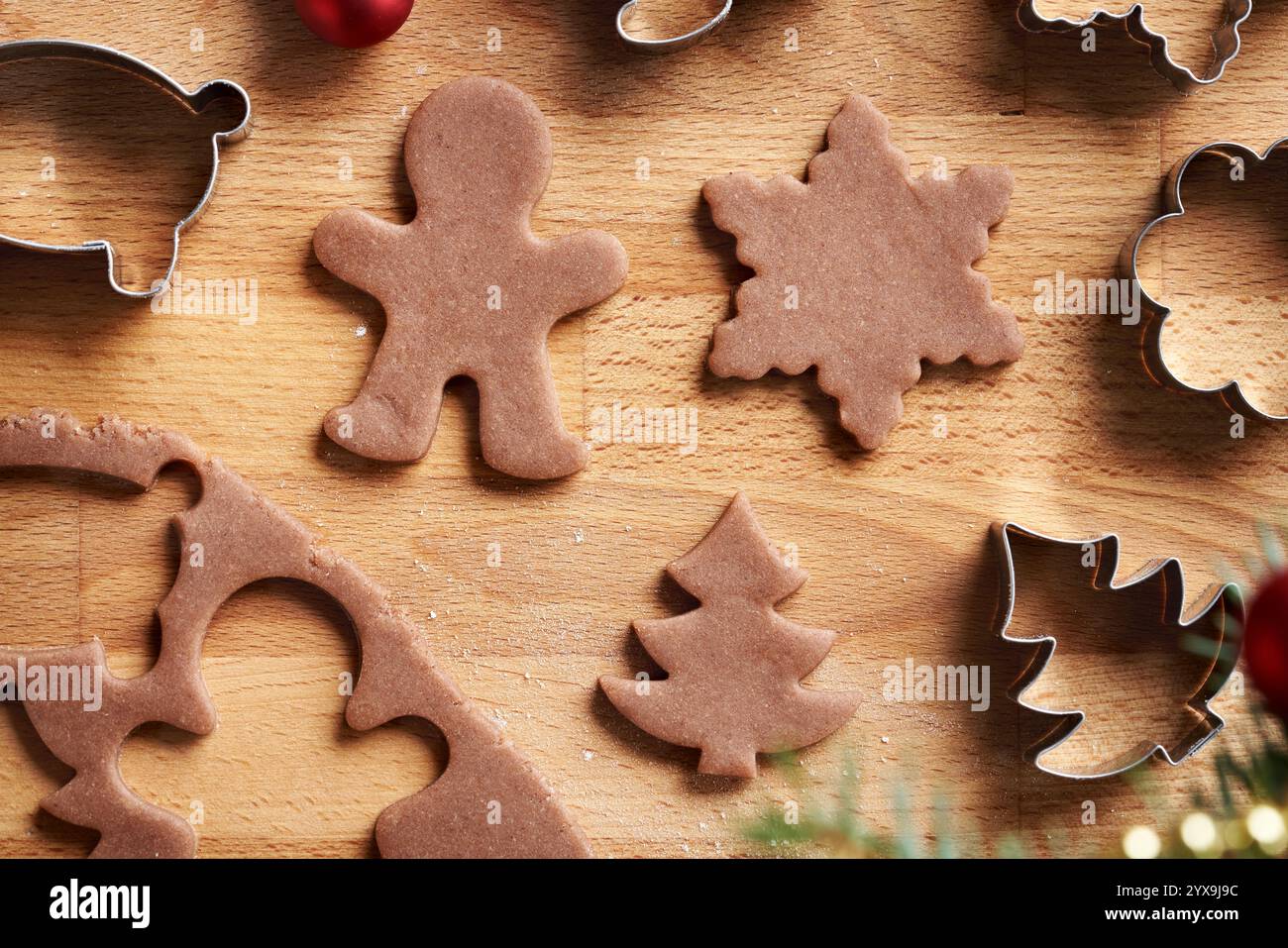 Varie forme tagliate dall'impasto di pasta cruda - preparazione di biscotti di Natale fatti in casa di pan di zenzero Foto Stock
