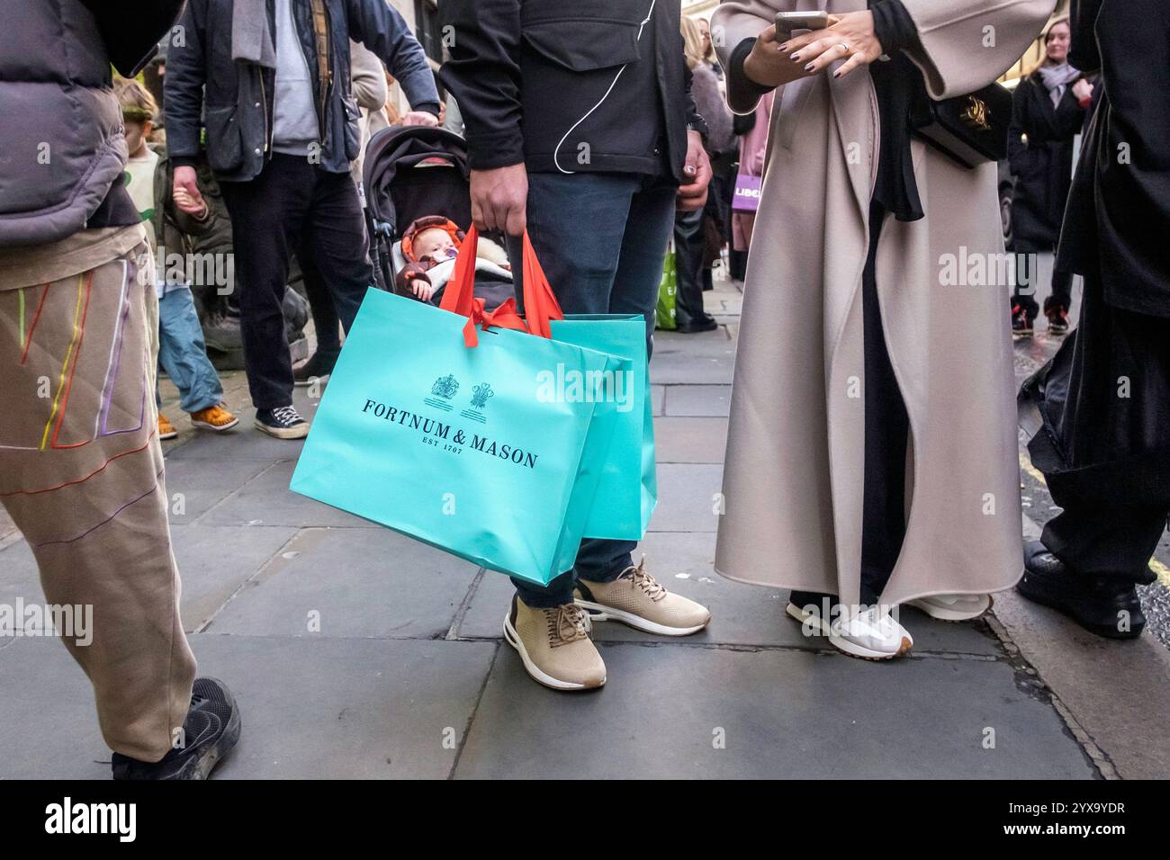 14 dicembre 2024, Londra. Gli amanti dello shopping natalizio che trasportano borse dei grandi magazzini Fortnum e Mason durante una giornata intensa per i negozi del West End di Londra, in attesa di Natale. Foto Stock