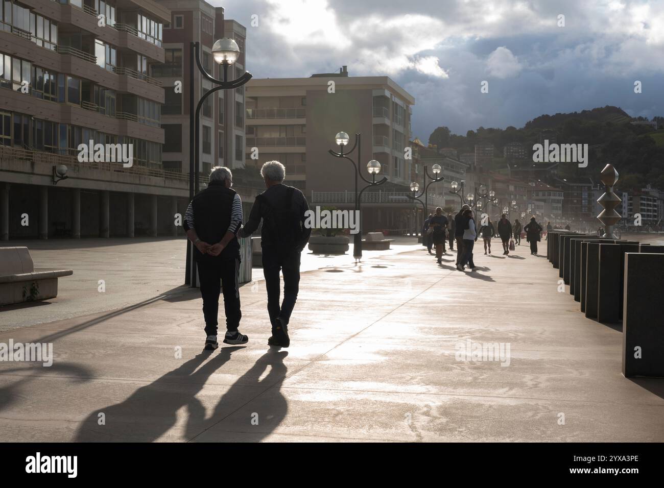 La gente del posto cammina lungo il Paseo Maritimo mentre il sole tramonta a Zarautz, Paesi Baschi, Spagna. Il popolare villaggio turistico si trova lungo il Camino del Norte Foto Stock