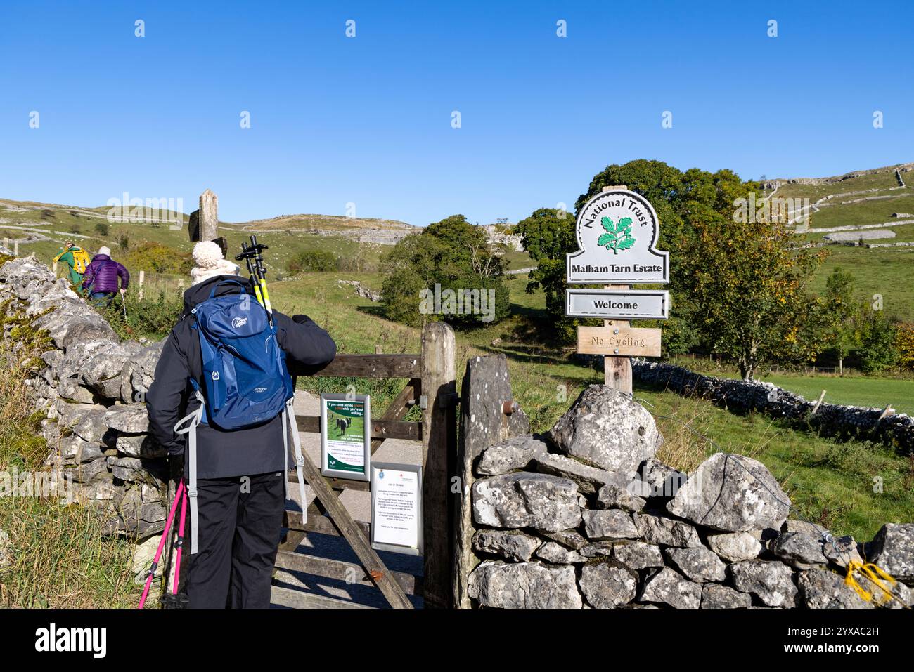 Donna escursionista nel parco nazionale Yorkshire Dales che si dirige verso la baia di Malham passa attraverso il cancello di legno, modello rilasciato, Inghilterra, Regno Unito, 2024 Foto Stock