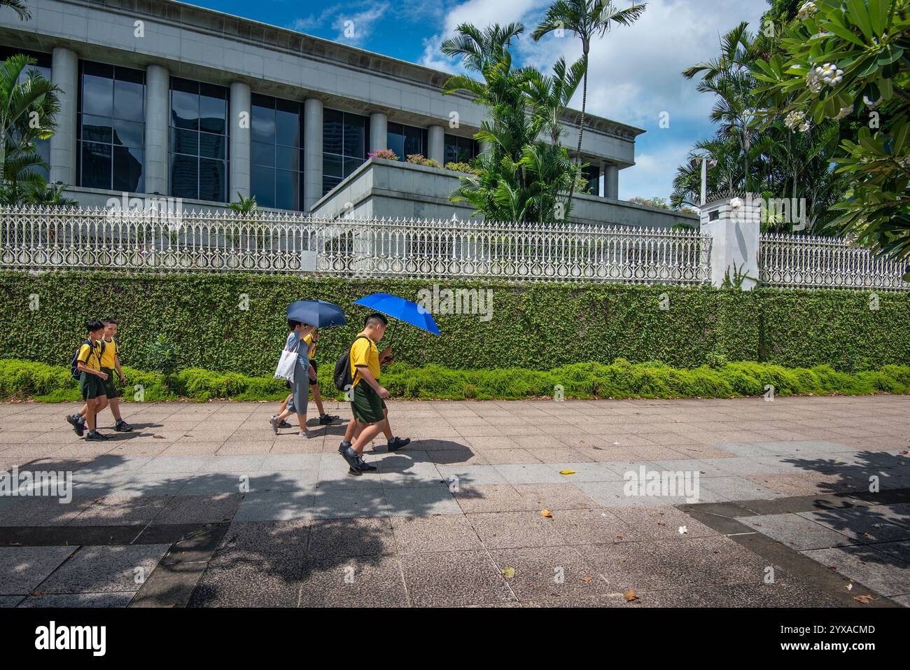 Bambini delle scuole minori che camminano lungo il fiume Singapore sul retro del Palazzo del Parlamento di Singapore Foto Stock