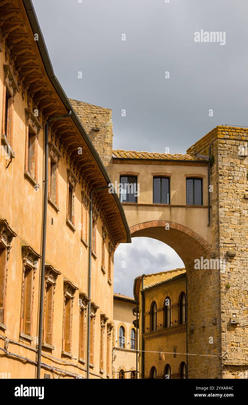 Ponte tra due edifici storici a Volterra, Italia Foto Stock