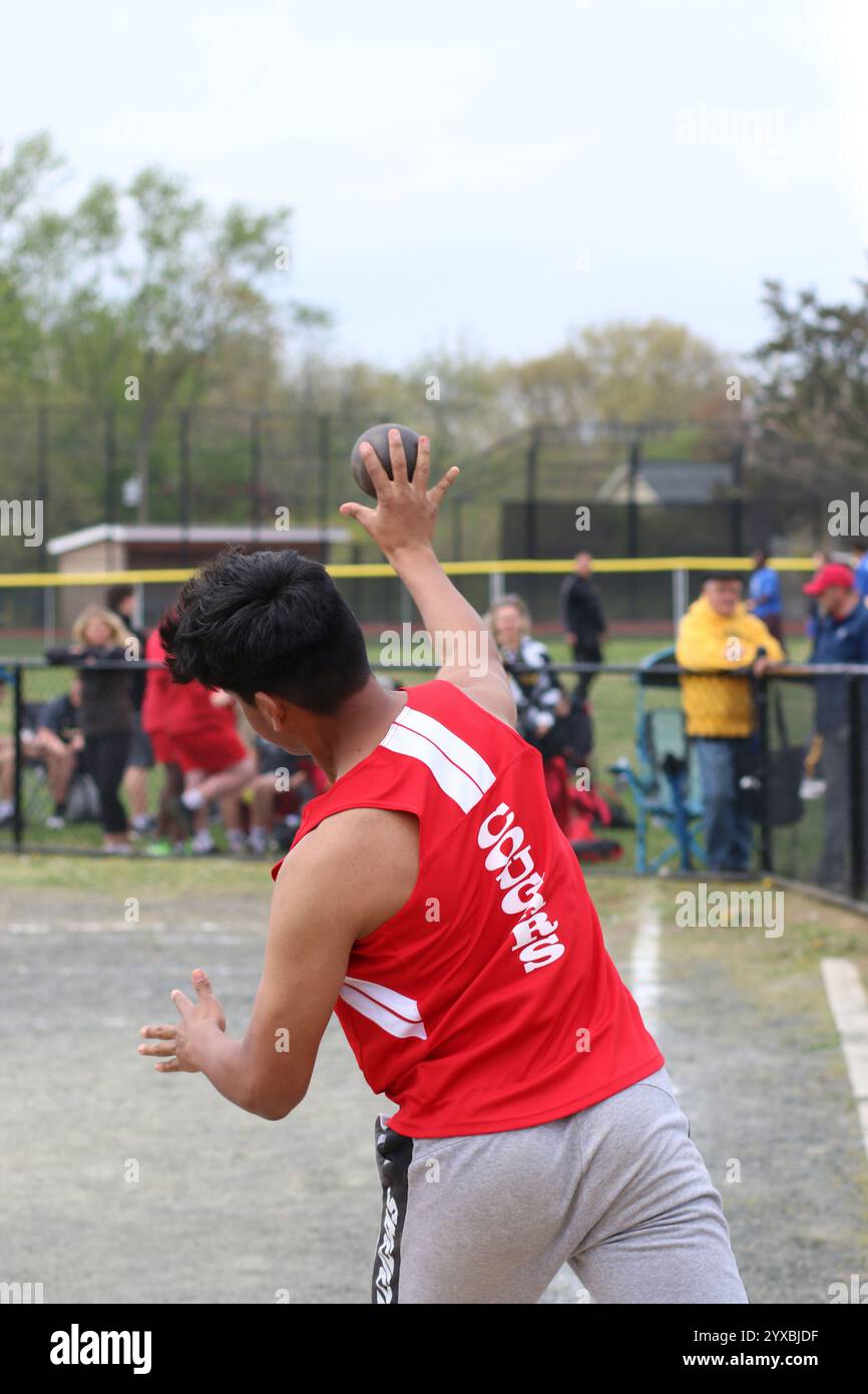 Commack, New York, Stati Uniti d'America - 22 aprile 2023: L'atleta studentessa si prepara a lanciare il tiro in un evento all'aperto competitivo mentre gli spettatori guardano. Foto Stock