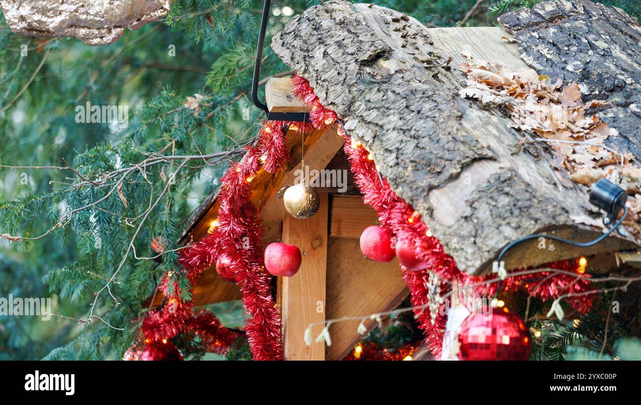 Decorazioni natalizie rustiche con ghirlanda rossa e tetto in legno nella natura Foto Stock
