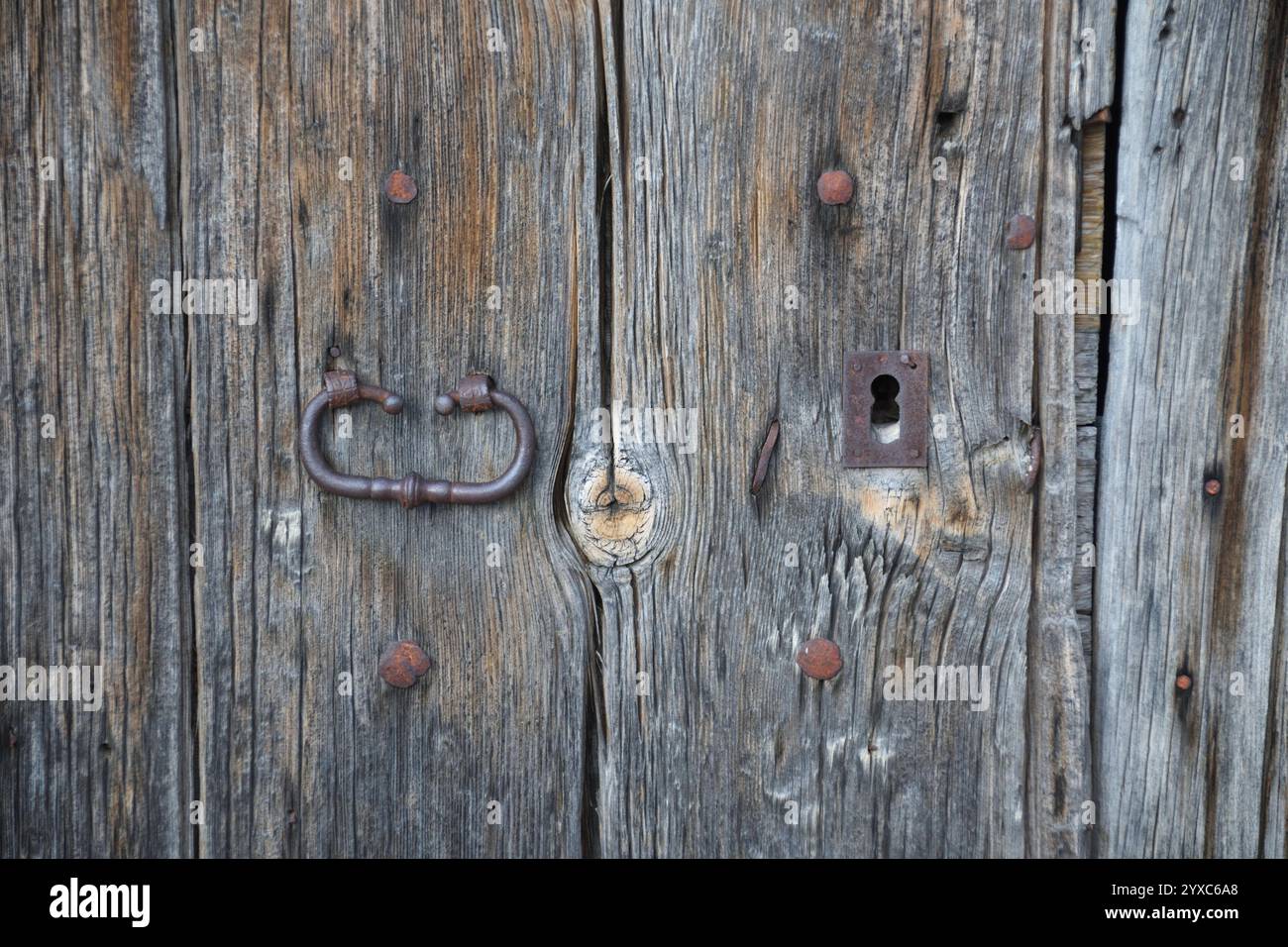 Primo piano di una vecchia porta in legno con una serratura antica, che mette in risalto la consistenza del legno invecchiato e i dettagli in metallo rustico, catturandone il fascino. Foto Stock