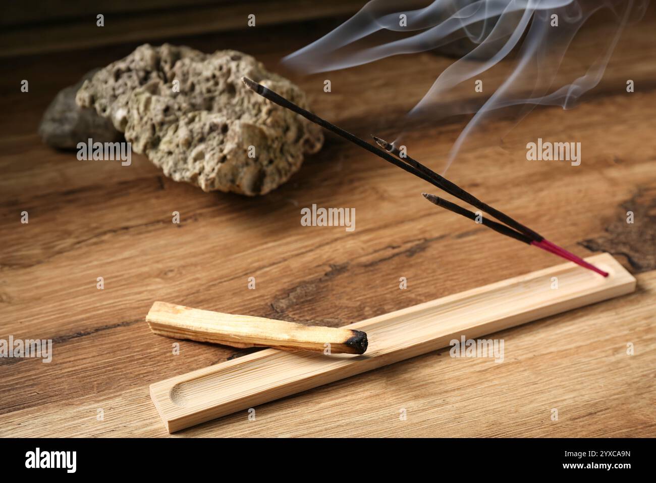 Supporto con bastoncini per incenso, Palo Santo e pietre su tavolo in legno Foto Stock