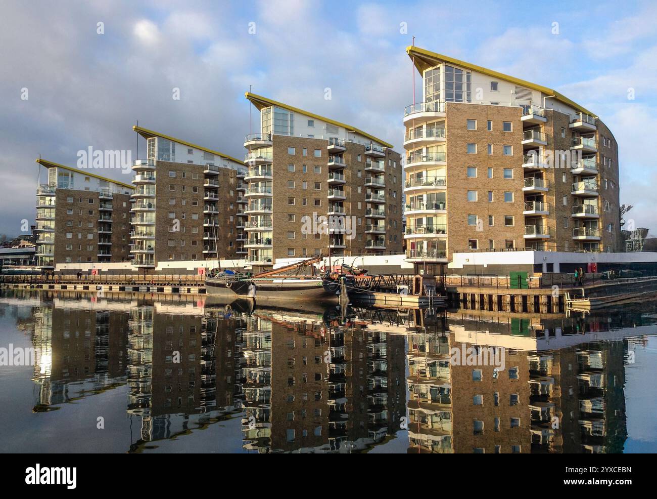 Moderni edifici di appartamenti con vecchie barche ormeggiate sul fiume Lee riflesse nell'acqua, Londra, Inghilterra, Regno Unito Foto Stock