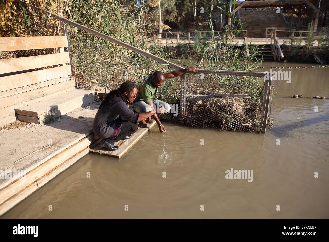 Uomo e donna ghanese, pellegrini cristiani evangelici, hanno messo le mani sul fiume Giordano a Qasr El Yahud, dove Giovanni Battista ha battezzato Gesù Cristo. Foto Stock