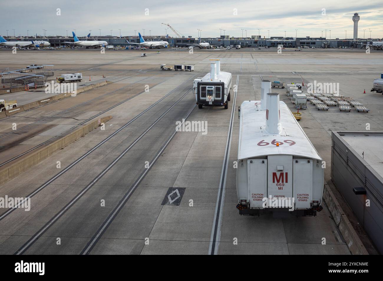 Una vivace scena all'aeroporto Dulles di Washington, con autobus che passano tra i terminal, incorniciati dalla torre di controllo e aerei a terra. Foto Stock