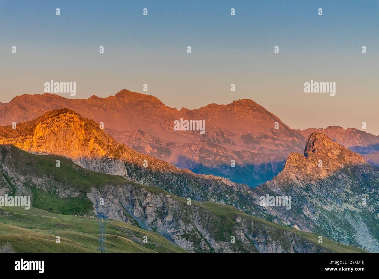 Tramonto in montagna. Luce rossa sul cielo con alcune nuvole sopra le splendide vette delle montagne e le cime innevate delle Alpi. Bellissimi cieli in fiamme Foto Stock