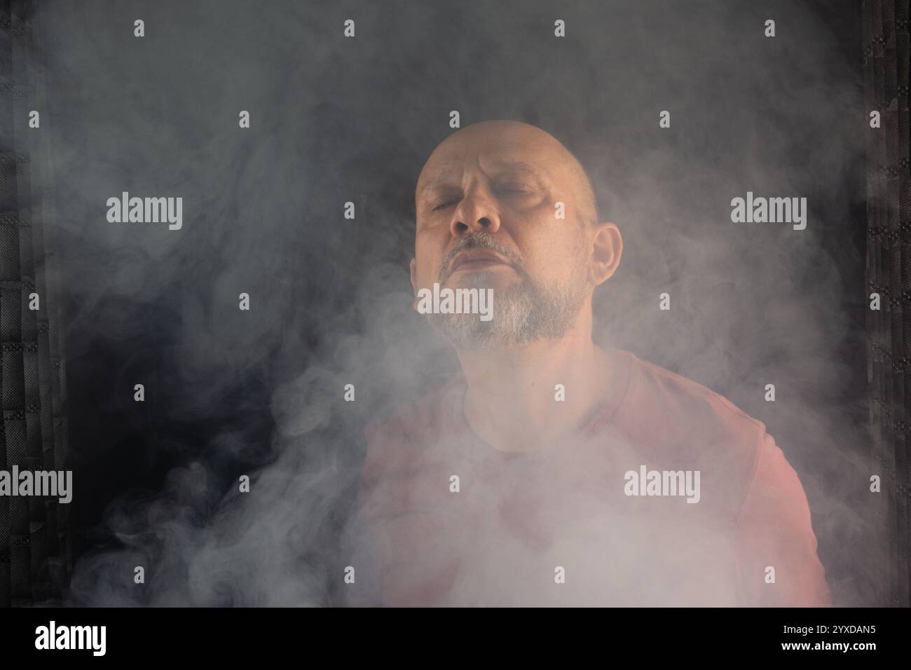 Uomo bianco, calvo, barbuto ad occhi chiusi. Ritratto in studio con sfondo nero fumé. Persona sudamericana. Foto Stock