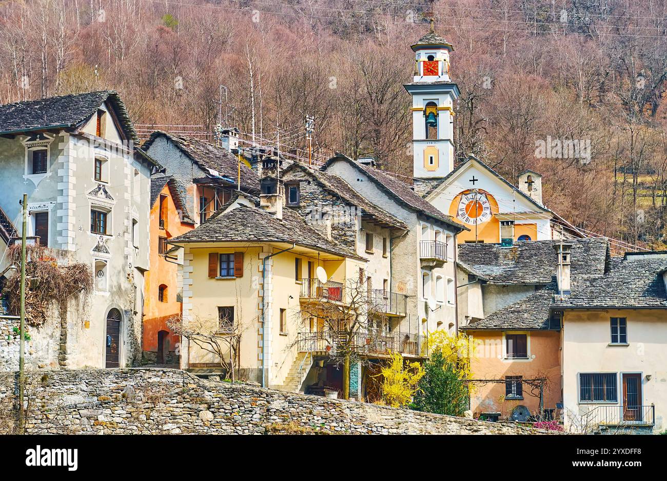 L'alto campanile della chiesa medievale di San Sebastiano e San Fabiano è visibile dietro i tetti in lastre di pietra delle case di Prato Sornico, Val Lavizza Foto Stock