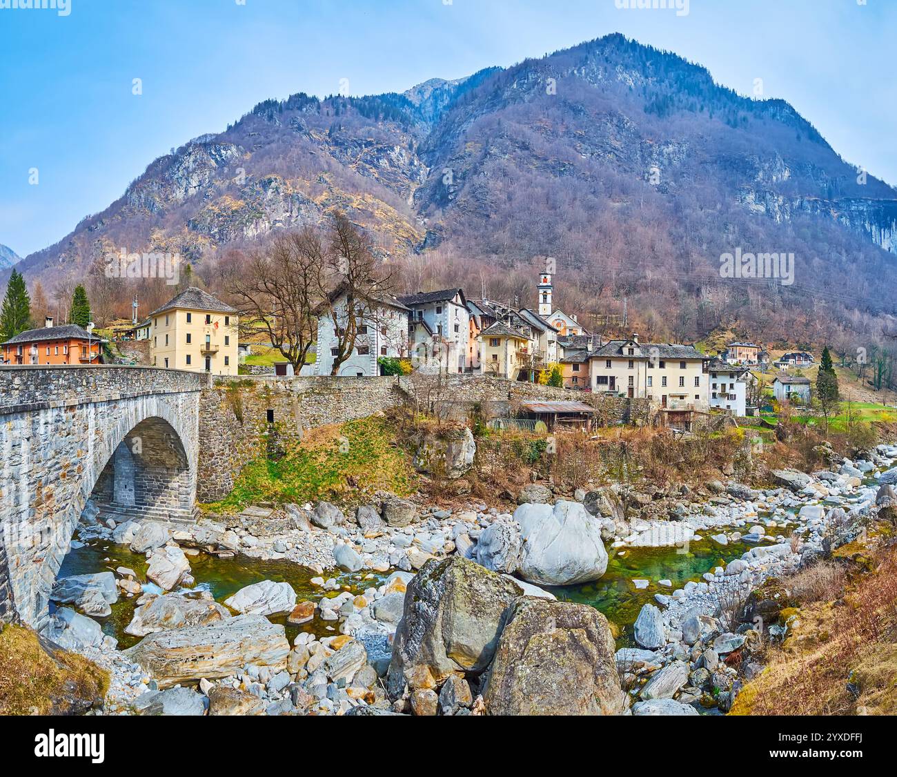 Panorama della montagna rocciosa del fiume Maggia, ponte ad arco in pietra e Prato Sornico medioevale contro le rocciose Alpi Lepontine, ricoperte di boschi, va Foto Stock