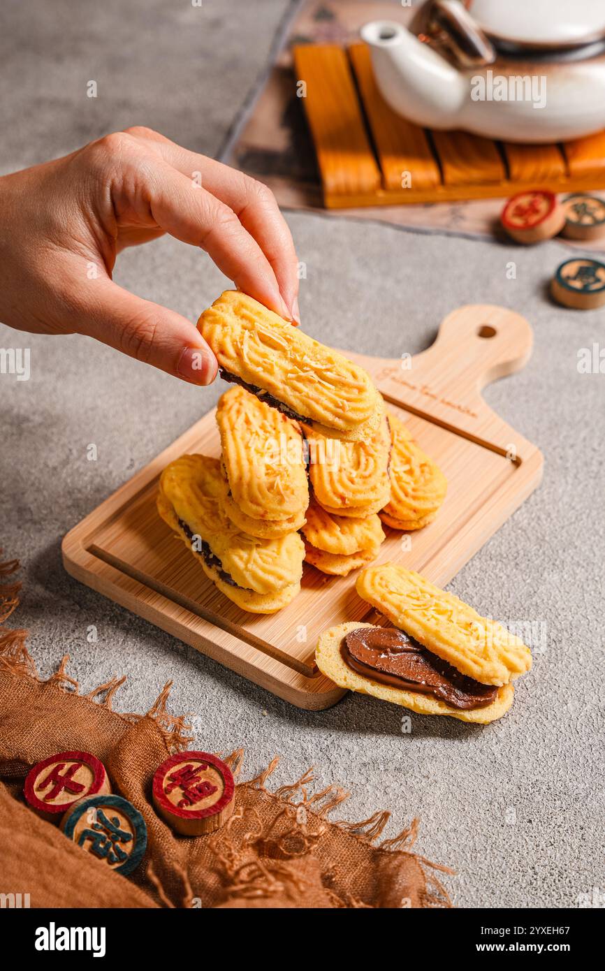 Il Kue lidah che si mescola con la marmellata di cioccolato è un piccolo biscotto indonesiano (kue kering) a forma di lingua di un gatto (lungo e piatto). Sono dolci e.. Foto Stock