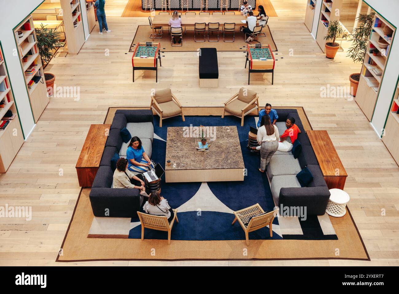 Un'immagine in alto di una lounge d'ufficio contemporanea con persone diverse che lavorano e socializzano. Le comode disposizioni dei posti a sedere promuovono Foto Stock