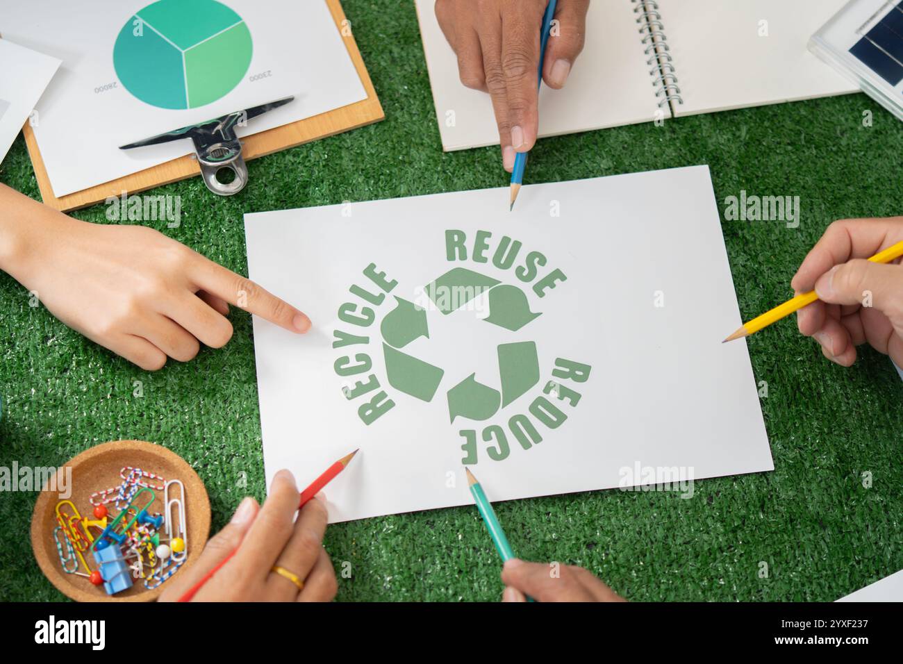 Un gruppo coeso di persone che indicano il simbolo di consapevolezza ambientale come responsabilità aziendale ecologica per la comunità Foto Stock