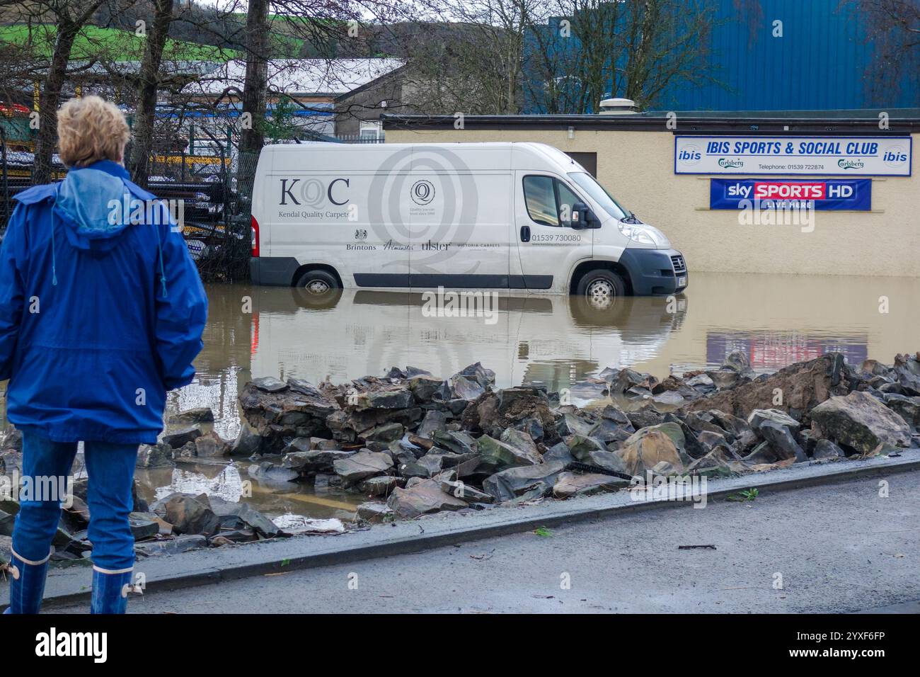Donna che guarda gli effetti devastanti della tempesta Desmond con la vista di un furgone parzialmente sommerso e del muro collassato. Foto Stock