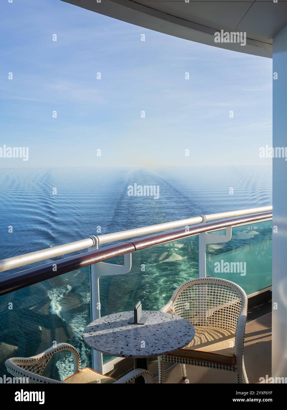 Vista da un'area salotto appartata sul retro di una nave da crociera che guarda verso un mare calmo e blu in una giornata luminosa e soleggiata. Concetto: Pace, calma e tranquillità Foto Stock