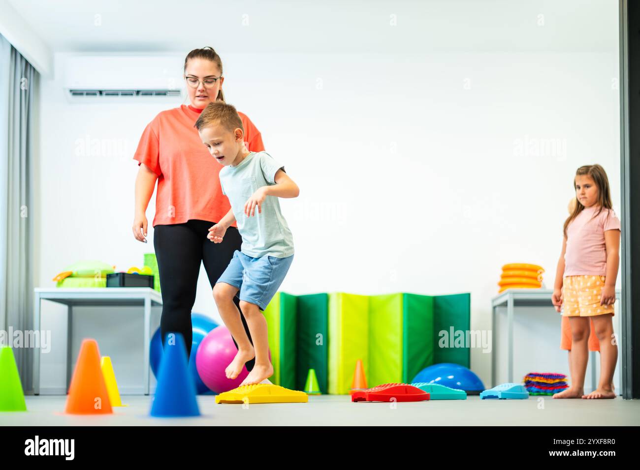 Bambini e terapeuta femminile durante la sessione di terapia fisica. Bambini che si allenano in fisioterapia di gruppo. Foto Stock