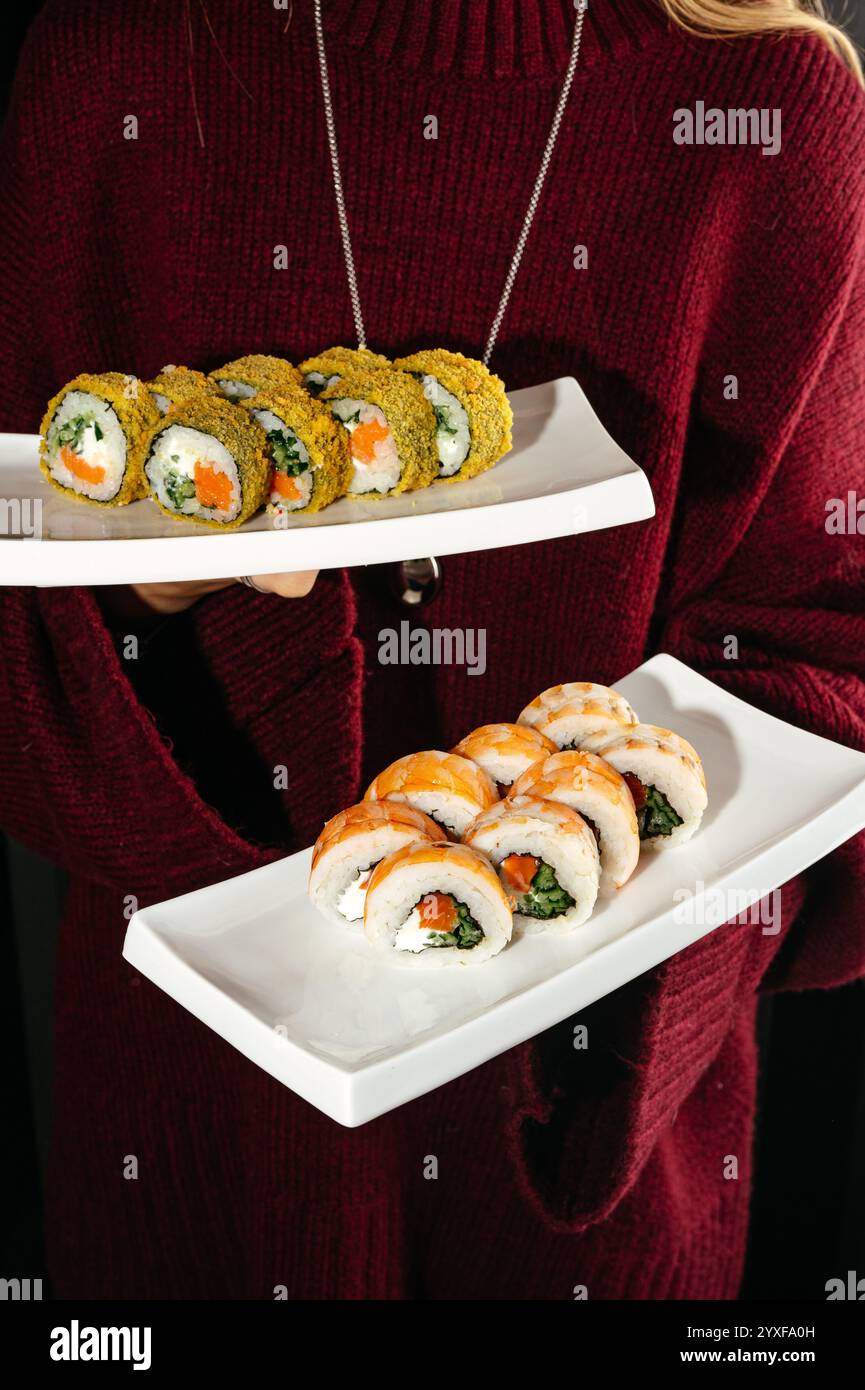 sushi roll con gamberi e panini al forno con pesce rosso sui piatti Foto Stock