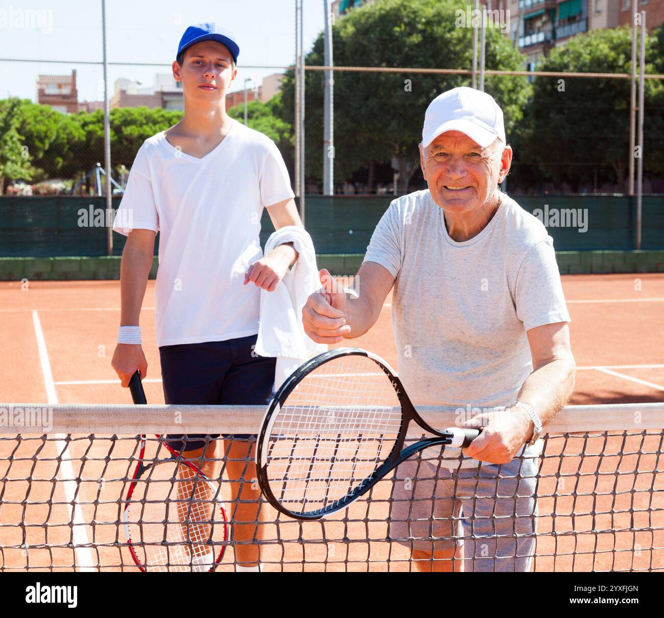 Nonno e nipote in posa sul campo da tennis Foto Stock