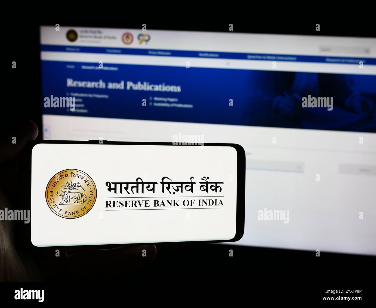 In questa immagine, una persona ha in mano un telefono cellulare con il logo della banca centrale indiana Reserve Bank of India (RBI) davanti alla pagina Web. Foto Stock