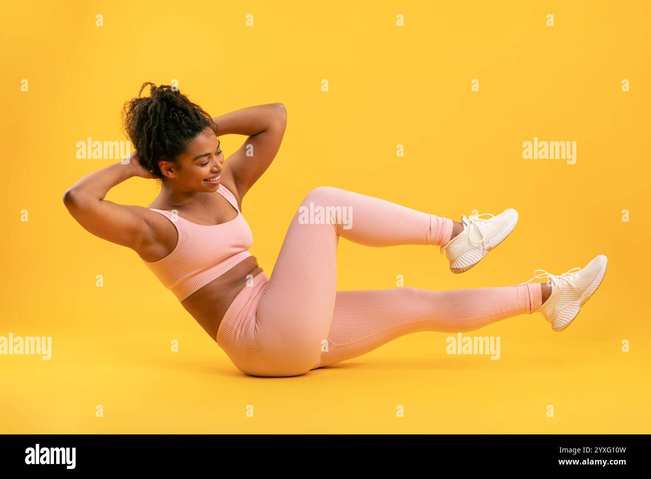 Donna che fa una routine di esercizio su uno sfondo giallo brillante Foto Stock