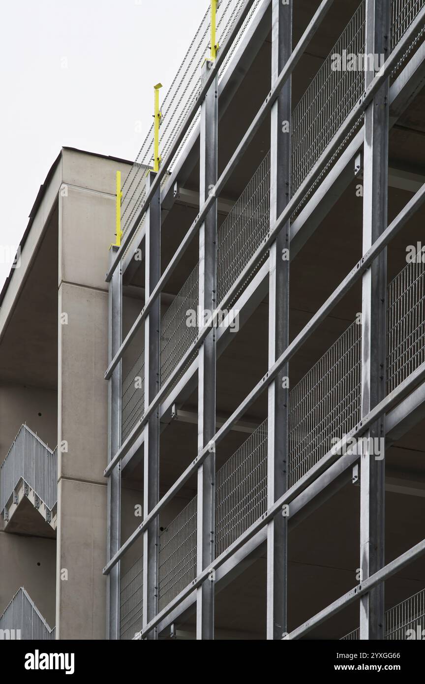 Struttura di parcheggio a più piani in acciaio e cemento dal design moderno con travi a vista e facciata in rete metallica Foto Stock