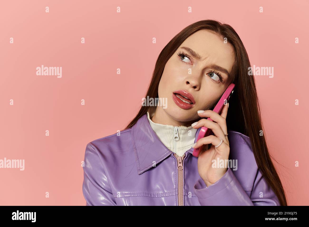 Una bella donna è impegnata in una conversazione telefonica, mostrando il suo look elegante e la sua energia vibrante. Foto Stock