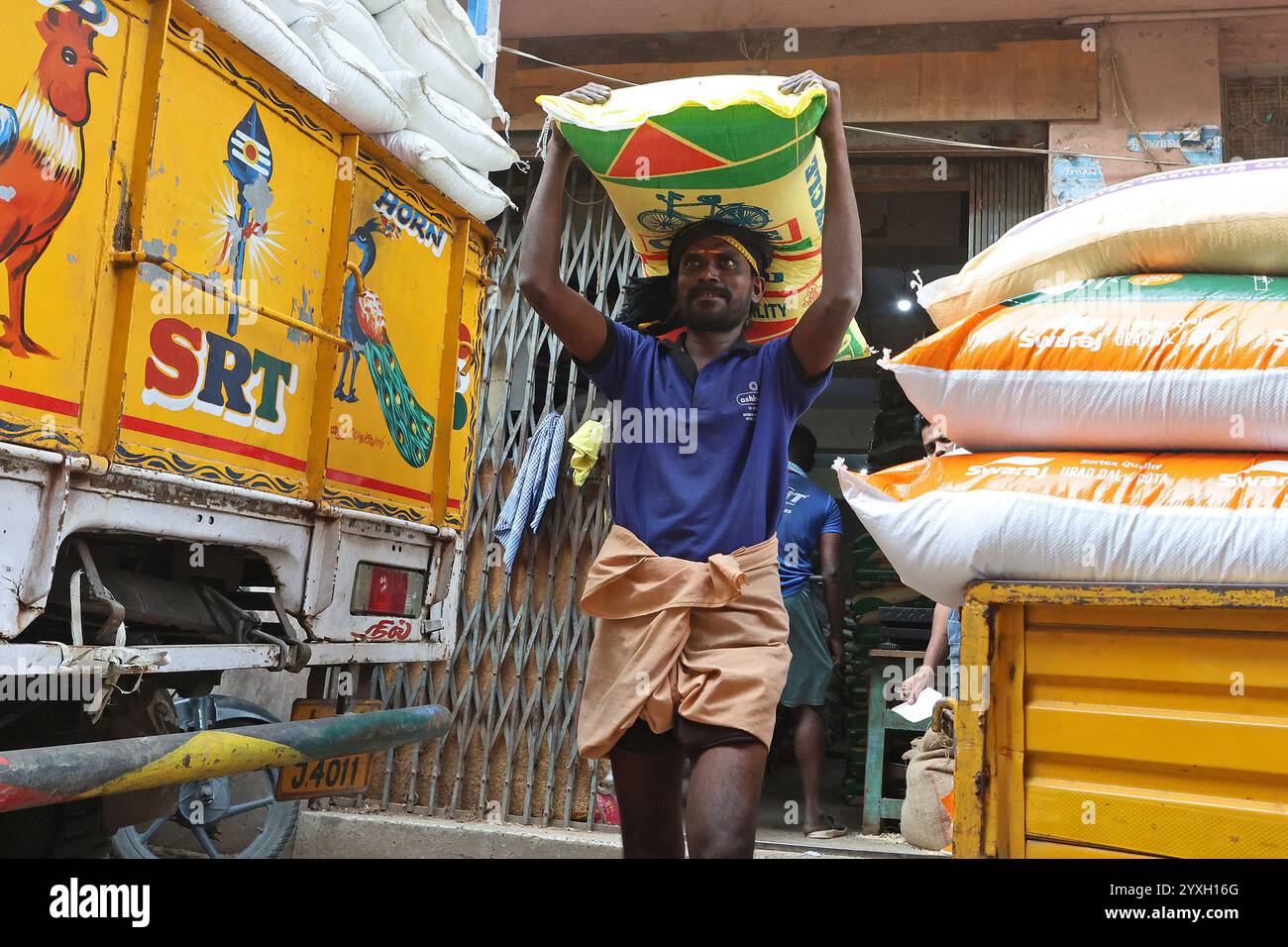 Un coolie che porta un sacco pesante sulla testa nel distretto George Town di Chennai, Tamil Nadu, India Foto Stock