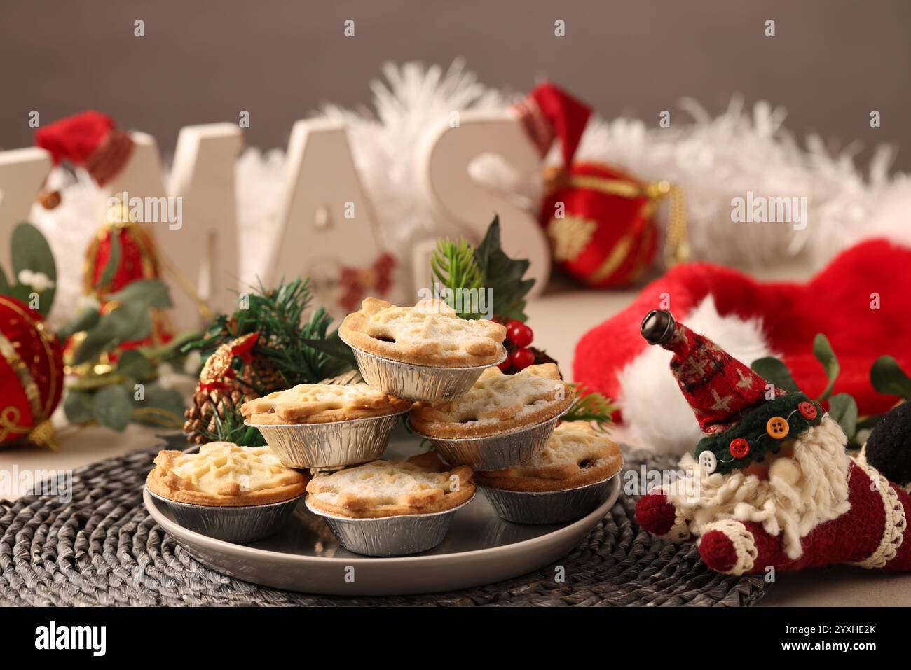 Un tavolo di natale con la parola "NATALE" in caratteri a blocco, c'è un piatto di tre torte tritate o tritate dragate con una salsa di zucchero Foto Stock